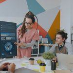 Equipe de profissionais analisa dados exibidos em um monitor durante reunião em escritório.