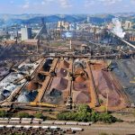 Vista aérea de uma instalação de mineração no Brasil, com máquinas industriais e pilhas de escória.