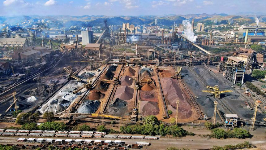 Vista aérea de uma instalação de mineração no Brasil, com máquinas industriais e pilhas de escória.