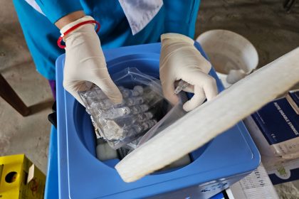 Profissional usando luvas manipula frascos em um laboratório.